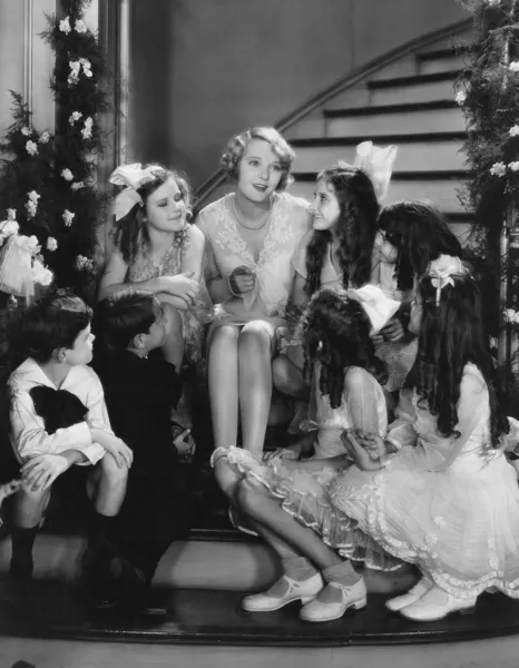 クリスマスに階段で子供たちと歌っている女性 — ストック写真