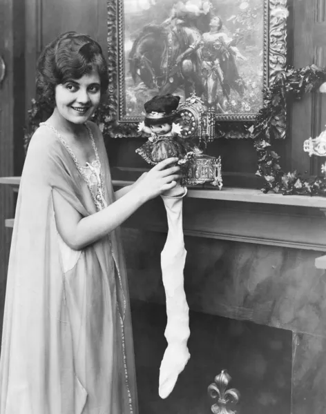 Smiling woman stuffing Christmas stocking — Zdjęcie stockowe