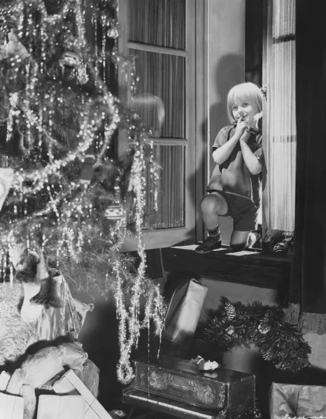 Niño admirando el árbol de Navidad y regalos de la ventana —  Fotos de Stock