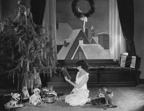 Teenage girl reading book with Christmas tree — Stock Photo, Image