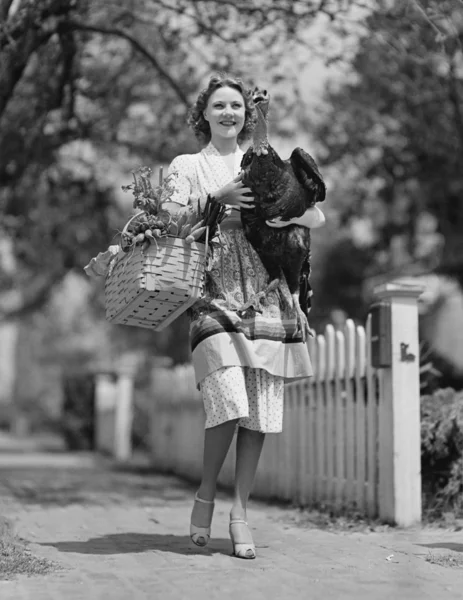 Mujer llevando pavo vivo y canasta de comestibles — Foto de Stock
