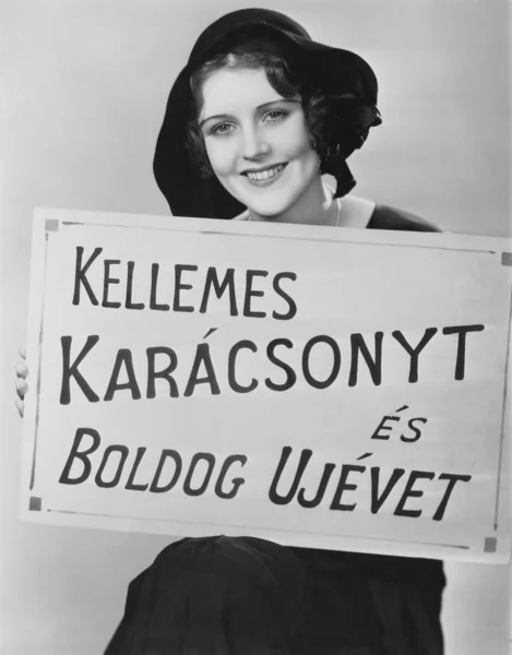 Portrait of woman holding sign written in foreign language — Stock Photo, Image