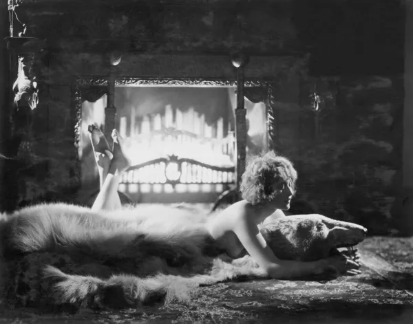 Женщина отдыхает на медвежьем ковре перед огнем — стоковое фото