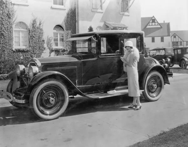 Vrouw met antieke auto buiten groot huis — Stockfoto