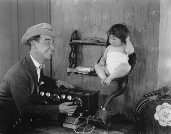 Father with baby in speaker horn of old radio