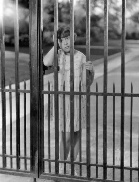 Portrait of girl through bars of fence — Stock Photo, Image