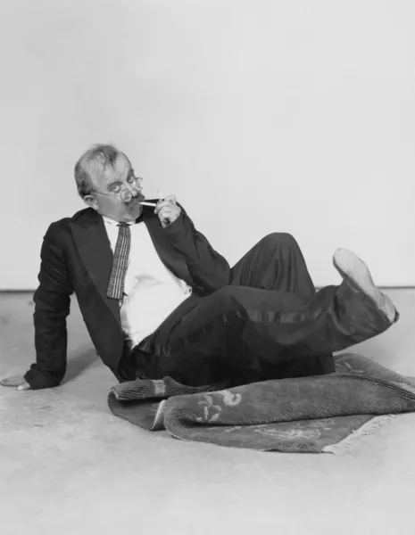 Άνδρας κάθεται στο πάτωμα φωτισμού τσιγάρων — Φωτογραφία Αρχείου
