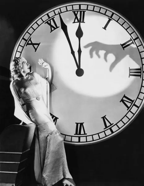 Woman with huge clock recoiling from frightening hand — Stock Photo, Image
