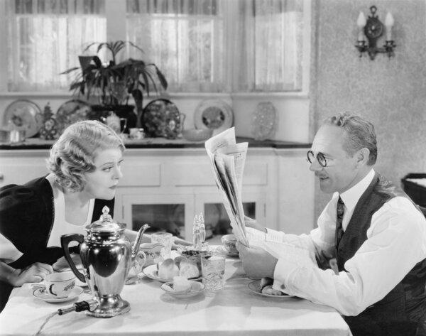 Couple reading newspaper at breakfast table