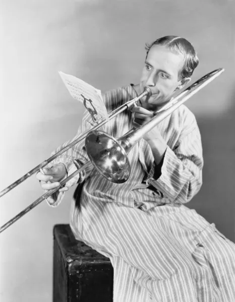 Hombre jugando trombón en camisón — Foto de Stock