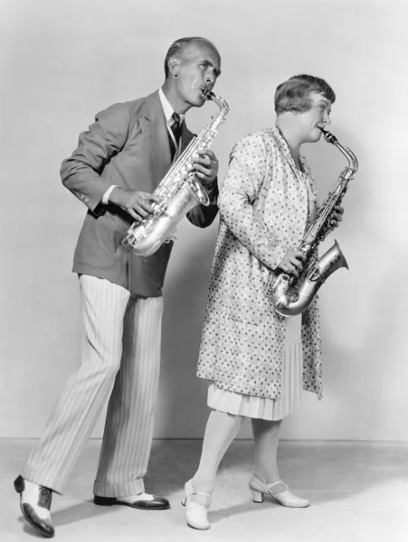 Casal tocando saxofones juntos — Fotografia de Stock