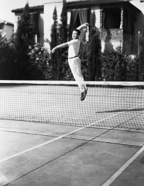 Male tennis player jumping for shot — Stock Photo, Image