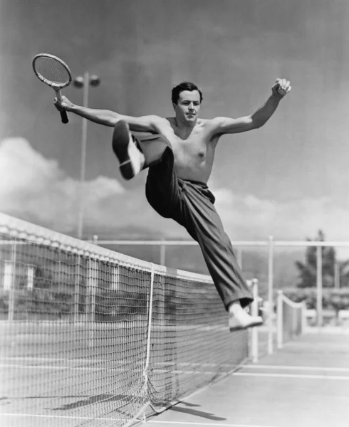 Теннисист прыгает через сетку — стоковое фото