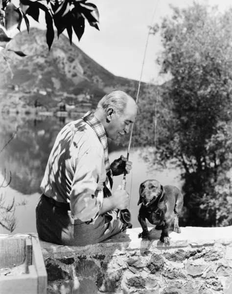 Viejo pescando con perro pequeño — Foto de Stock