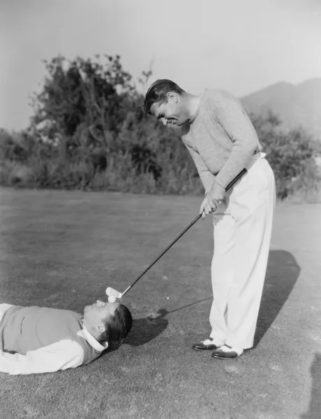 Homem batendo bola de golfe na testa dos homens — Fotografia de Stock