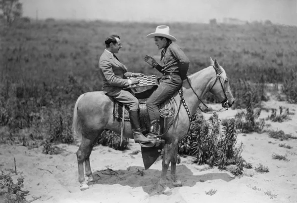 Cowboy and businessman playing checkers on horseback — Stock Photo, Image