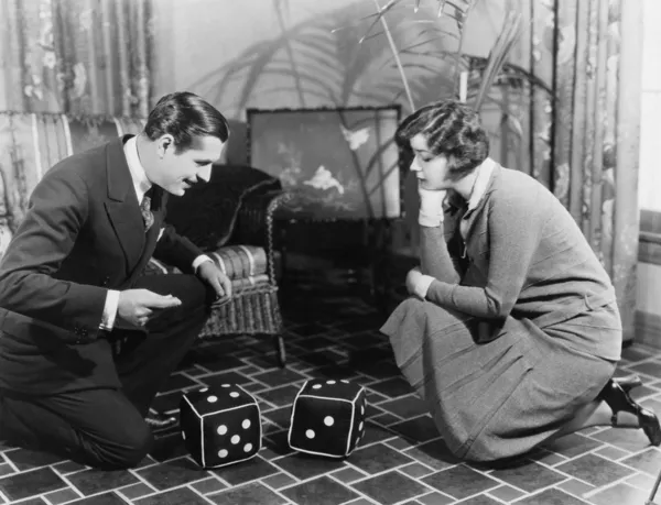 Couple playing with huge dice — Stock Photo, Image