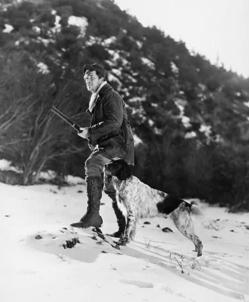 Homem caçando em montanhas nevadas com cão — Fotografia de Stock