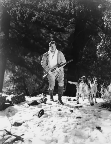 Muž na lovu v zasněžených lesích se psy — Stock fotografie