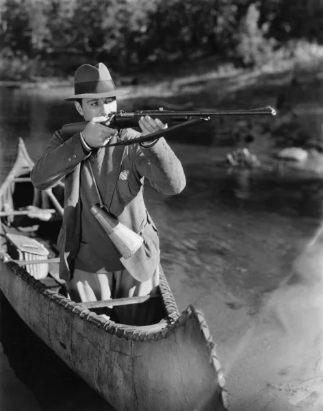 Homem apontando arma de canoa — Fotografia de Stock