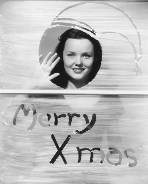 Woman waving at window with Christmas greeting Stock Photo