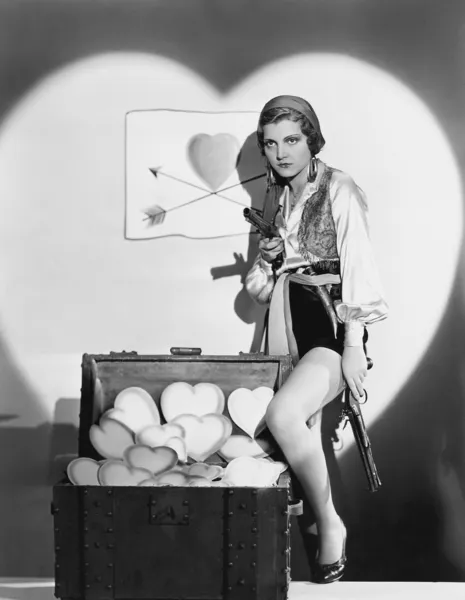Портрет женщины с оружием и сундуком, полным сердец — стоковое фото