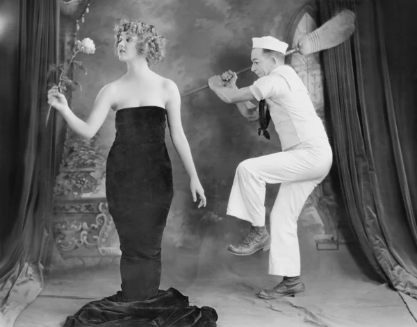Sailor hitting elegant woman with broom Stock Picture