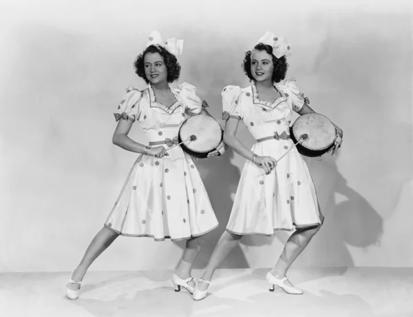 Женщины в одинаковых нарядах играют на барабанах Стоковое Фото