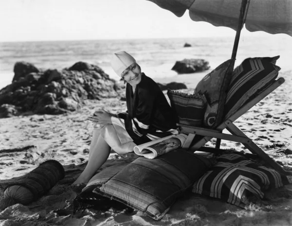 Frau entspannt sich unter Sonnenschirm am Strand Stockbild
