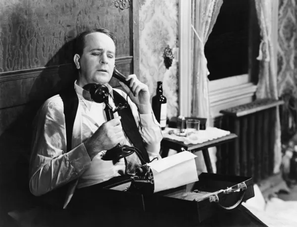 Homem com máquina de escrever a falar ao telefone Fotografia De Stock