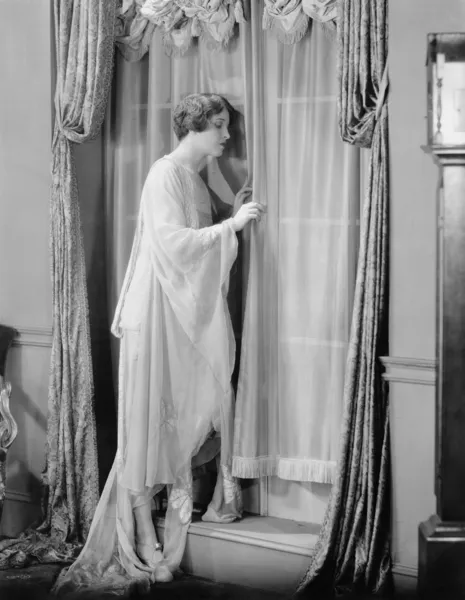 Mujer asomándose por la ventana Imagen de archivo
