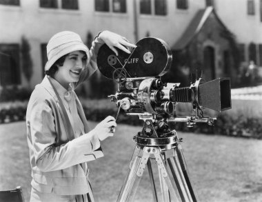 Woman using movie camera outdoors clipart