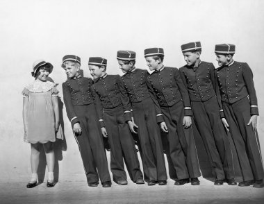 Line of young bellhops smiling at girl clipart