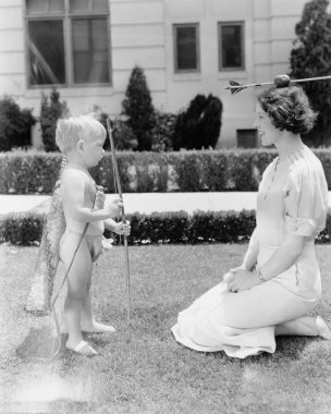 Baby cupid shooting apple on womans head clipart