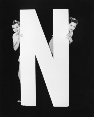 Two women hiding behind huge letter N