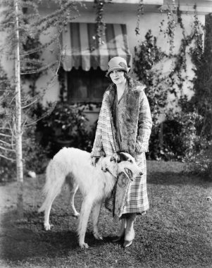 Young woman in coat and hat standing outside with her Russian Wolfhound clipart