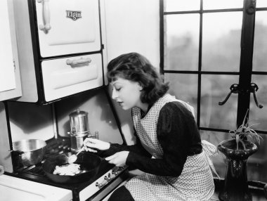 Woman in her kitchen preparing food on the stove clipart