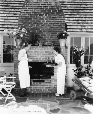 Man and woman at their barbecue in the back yard clipart