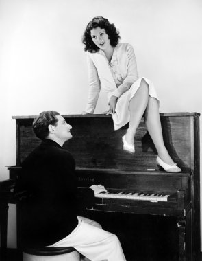 Woman singing on an upright piano with a friend playing clipart