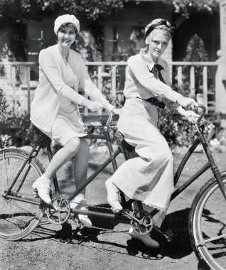 iki kişilik bisiklet üzerinde oturan iki genç kadın portresi