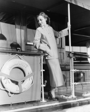 Young woman standing at the railing of a boat clipart