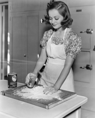 Young woman pouring water into flour clipart