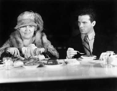 Woman and young man sitting at a coffee counter clipart