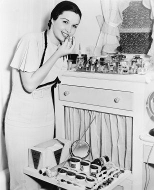 Young woman at her vanity applying lipstick clipart