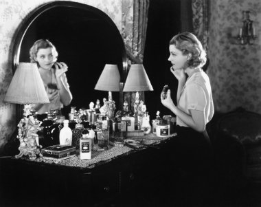 Young woman in front of her vanity applying make-up clipart