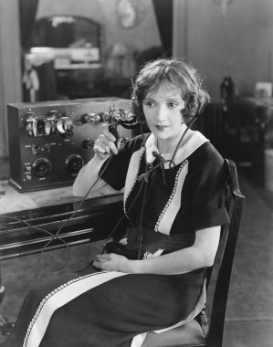 Switchboard operator sitting at telephone switchboard and talking clipart