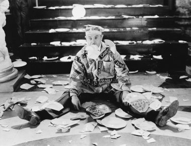 Man sitting in front of a staircase with broken plates around him clipart