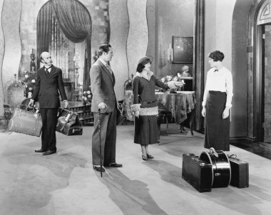 Four standing in a the lobby of a hotel with luggage clipart