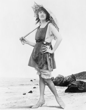 güneş şemsiyesi ve mayo sahilde bir kadınla