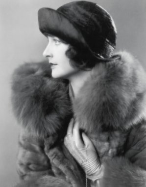 Profile of an elegant woman in a fur coat and satin hat clipart